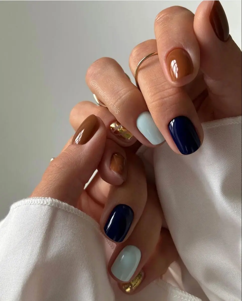 Mismatched caramel, espresso, navy and pale blue September manicure with gold foil accents
